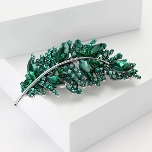 Close-up of emerald leaf brooch with sparkling crystals and silver metal base