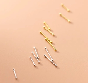 Macro shot of 999 sterling silver stud earrings in gold and silver finish with ball ends