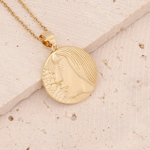 Macro detail of golden 18K zodiac pendant with relief face on textured stone background