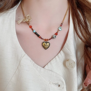 Detail of bohemian gold heart pendant with black rhinestones and multi-colored beads