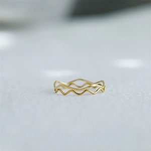 Close-up of a delicate gold-plated wave ring with a polished minimalist geometric design