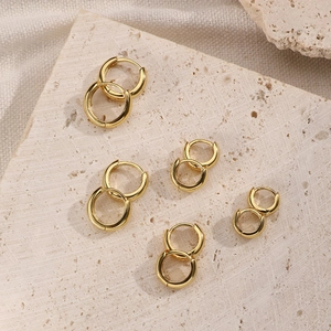 Set of five gold S925 sterling silver hoop earrings on a beige travertine stone display