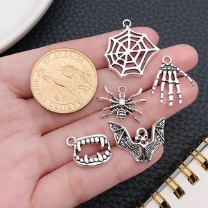 Size comparison of silver Halloween alloy charms next to a coin for scale