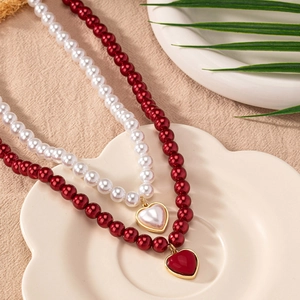 Elegant heart pendant pearl necklace set in red and white on a stylish white tray