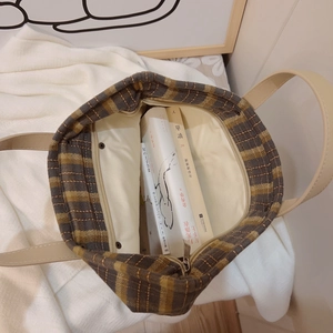 British style vintage plaid canvas tote bag with leather handles on a soft white knit rug