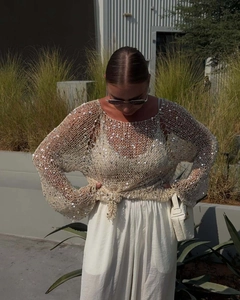 Detail of beige hollow-out knit sweater with silver sequins and lace-up bohemian hem