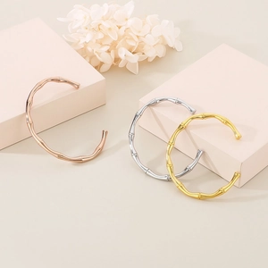 Bamboo-shaped open bangles in gold, silver, and rose gold stainless steel set on blocks