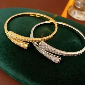 Close-up of gold and silver plated C-shaped open bangles with micro-set zircons on velvet