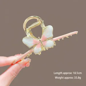 Close-up of golden butterfly hair claw clip with pink gradient wings and 10.5cm scale