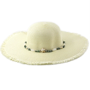 Detail of straw sun hat with beaded starfish band and raw fringe edge texture
