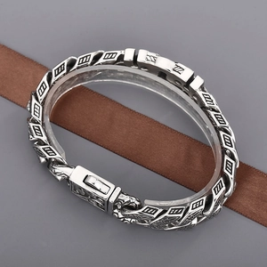 Dettaglio del bracciale punk in acciaio con incisioni retrò e chiusura in stile antico