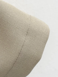 Detail shot of beige cotton linen fabric showing fine weave texture and stitching