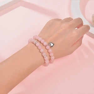 Pink natural stone beaded bracelet with silver heart charm and crystals on female wrist