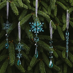 Detailed view of 5 blue acrylic snowflakes and icicles hanging on green pine branches