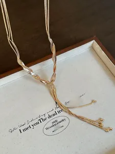 Close-up of golden multi-layered snake chain necklace with dangling tassel bead details