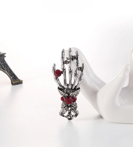 Close-up of retro punk skeleton hand brooch with dark red rhinestones on display