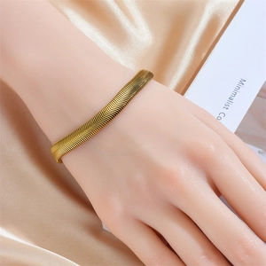 Elegant gold snake bone textured bangle with wavy pattern shown on wrist over silk