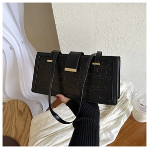 Detail of black faux crocodile leather texture and gold buckle on a stylish shoulder bag