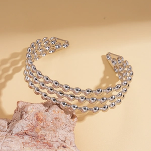 Dettaglio macro del bracciale a tre strati di perline argentate su pietra naturale