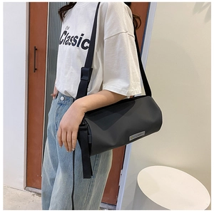 Vue détaillée d'un sac bandoulière cylindrique noir avec bandoulière réglable en tissu