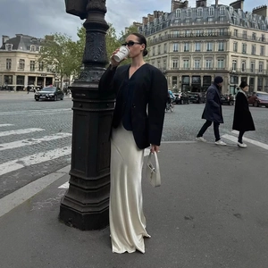 Blazer noir oversize élégant avec une jupe longue en satin crème dans les rues de Paris
