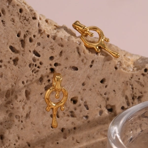 Macro view of gold-plated liquid lava earrings hanging on a natural porous rock texture