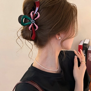 Détail d'une pince à cheveux à nœud tricolore portée par un mannequin pour le style