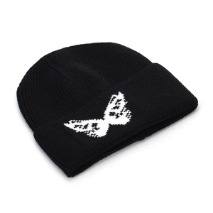 Black knit beanie with white butterfly jacquard pattern in a classic cuffed ribbed style
