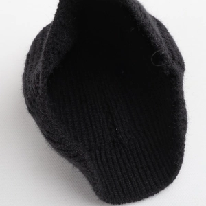 Detailansicht der inneren Strickstruktur und Textur einer schwarzen Zopfstrickmütze