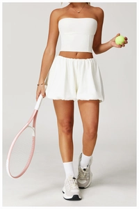 Close-up of white tennis sports set featuring a crop top and pleated athletic shorts