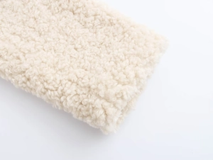 Nahaufnahme der weichen beigen Lammfell-Textur dieses flauschigen Wintermantels für Damen