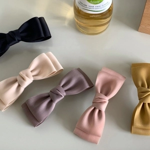 Elegant satin bow hair clips in five colors including black and beige on white background