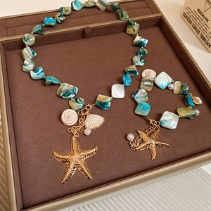Detail of starfish and shell charms on turquoise stone necklace and bracelet set