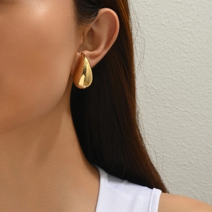 Close-up of a model wearing a gold waterdrop earring in polished stainless steel