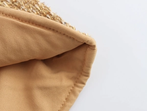 Detailed close-up of brown fabric lining and gold thread stitching on woven straw hat