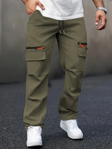 Outdoor shot of olive green cargo pants with drawstring waist and orange zipper details