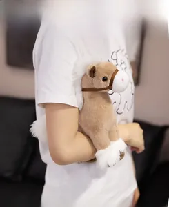 Detail of soft plush pony doll with white mane held by a person in cozy home setting