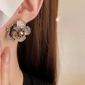Detailed close-up of vintage floral earrings with colorful crystals and pearls on ear