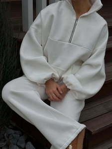 Detailed outdoor shot of a white half-zip sweatshirt and wide-leg jogger set on steps