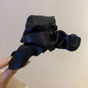 Close-up of black satin pleated fabric with subtle shimmer on a stylish hair claw clip