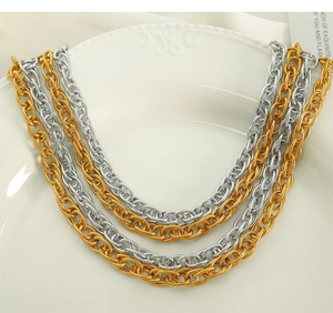 Close-up of stacked gold and silver intertwined chain necklaces on a white ceramic plate