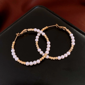 Detailed macro of 14K gold plated hoop earrings with twisted metal and white pearls