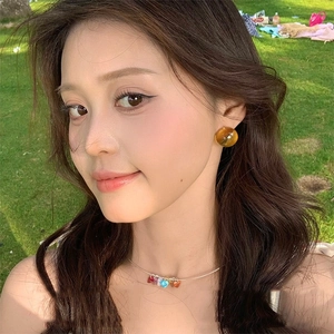 Colorful resin heart necklace and amber studs set on a model in sunlight outdoor