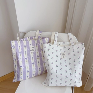 Detail of floral canvas tote bags with lavender patterns on a minimalist white chair