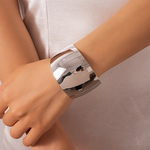 Close-up of a wide polished silver cuff bracelet with a mirror finish on a female wrist