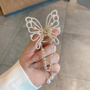 Detail of golden butterfly hair clip with pearl tassels and shimmering alloy framework