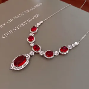 Luxury oval red gemstone pendant necklace with shimmering zircon accents on grey background