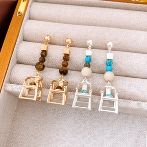Detail of unique chair-shaped earrings with pearls and stones in velvet jewelry box