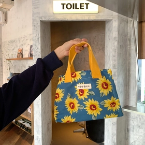 Detail of canvas lunch bag with yellow sunflower patterns and bright webbed handles