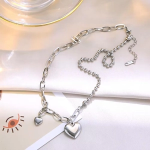 Chic silver necklace with heart pendants and unique mixed chain design on silk fabric